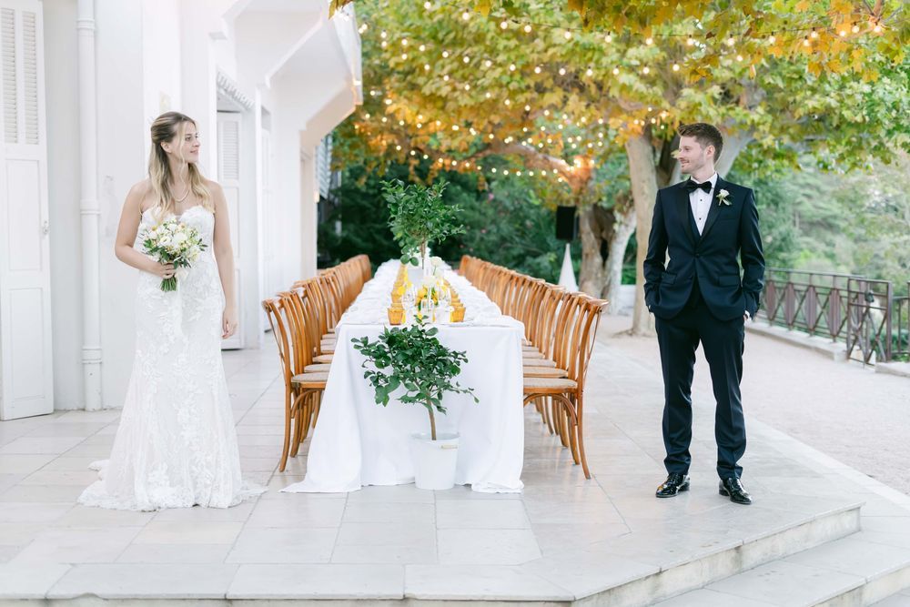 Couple embraces on a scenic overlook with ocean and coastline views during golden hour at their outdoor wedding.