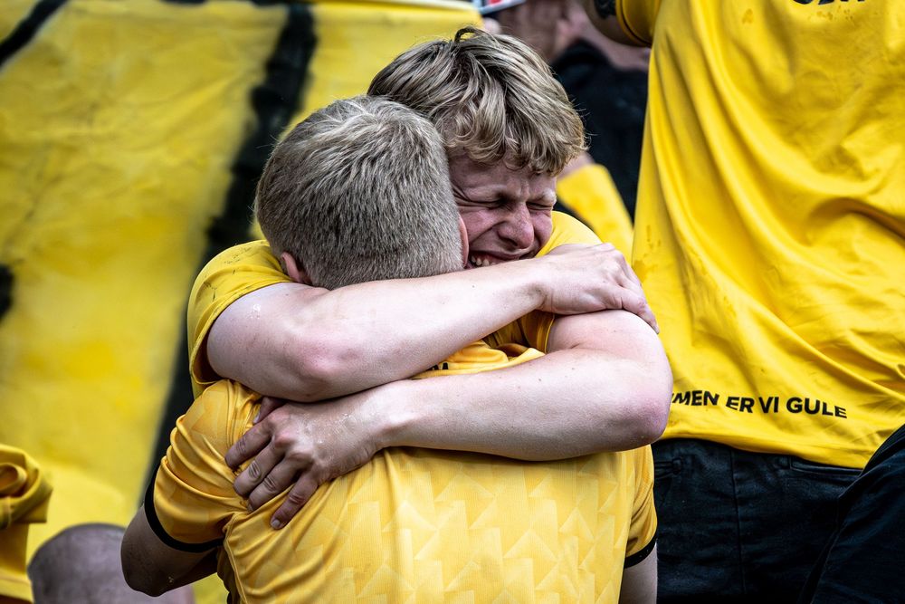Two young fans in yellow shirts share an emotional hug during a sports celebration event.