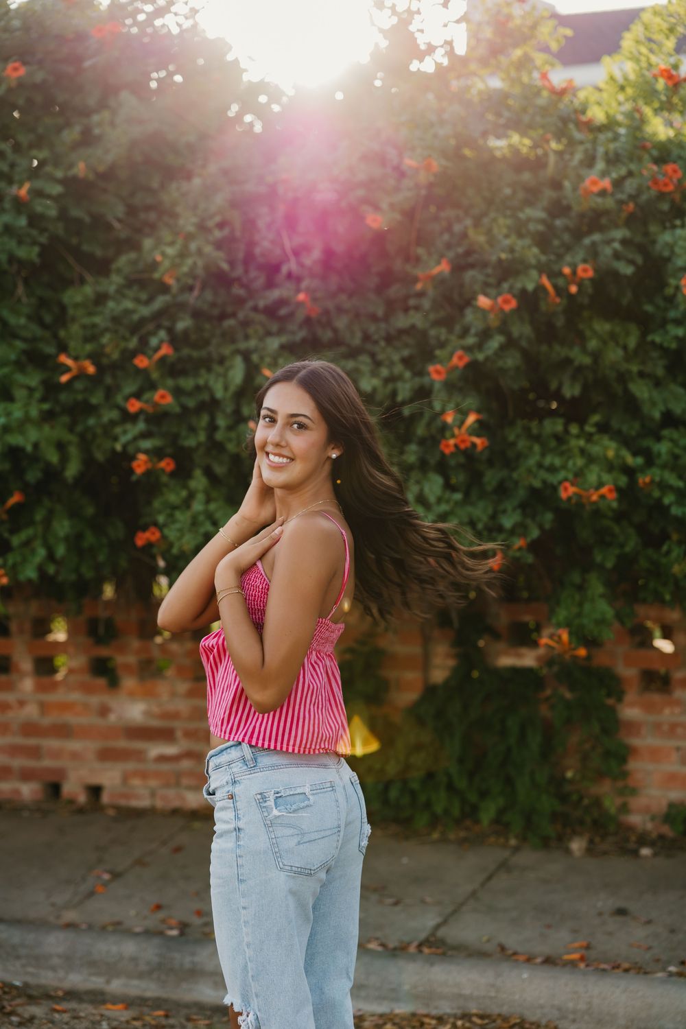 A girl taking senior photos posed in front of greenery and flowers in Tulia Texas