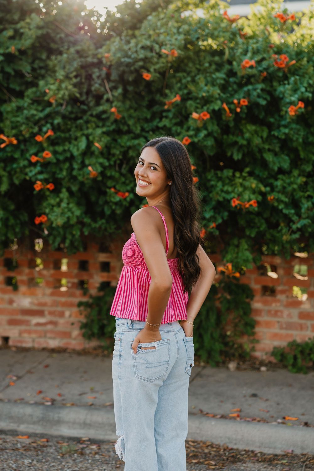 Tulia Senior taking portraits during golden hour in front of brick and greenery and flowers