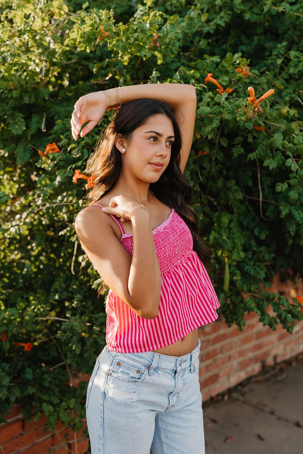 A girl having fun taking senior portraits in Tulia Texas wearing a pink top and ripped jeans