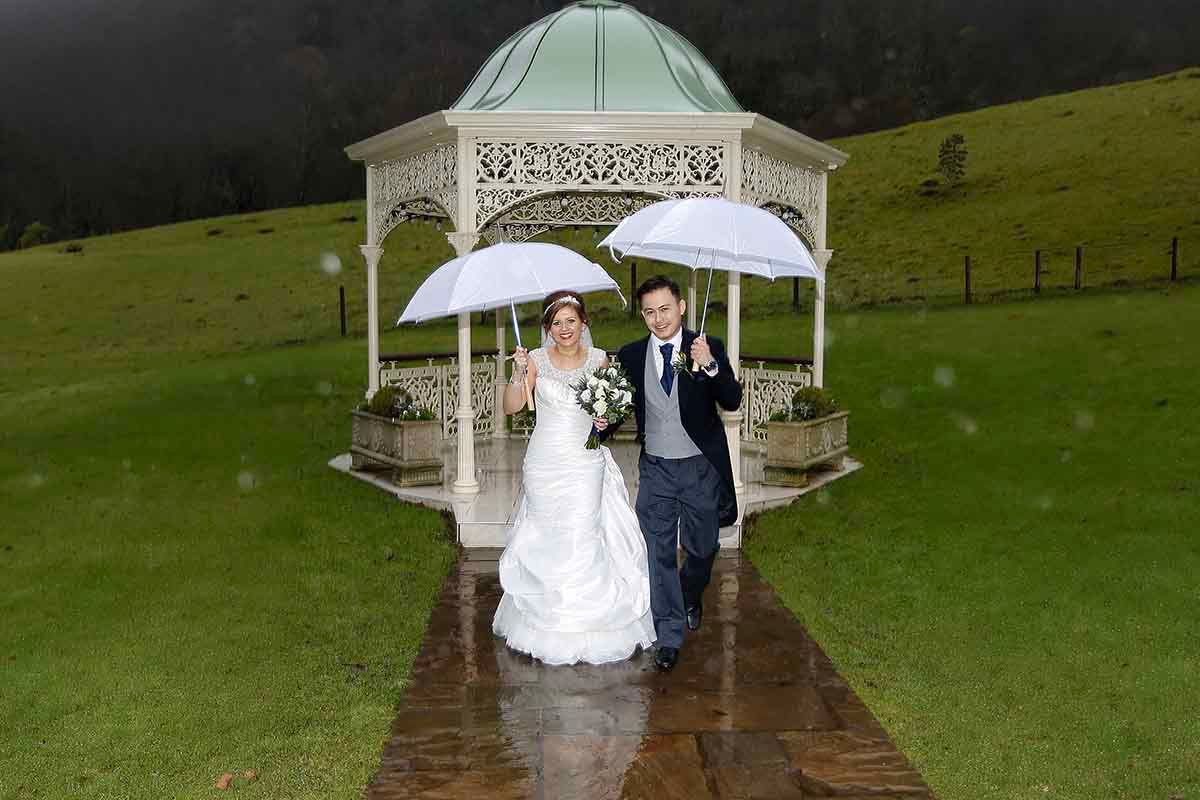 its not the Lake District if it doesn't rain, bride and groom run for shelter at lower falls hotel and spa
