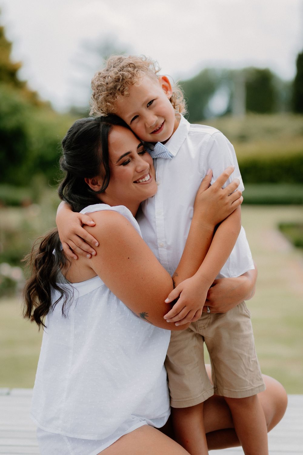 A tender embrace shared between two people wearing white outfits outdoors on a summer day.