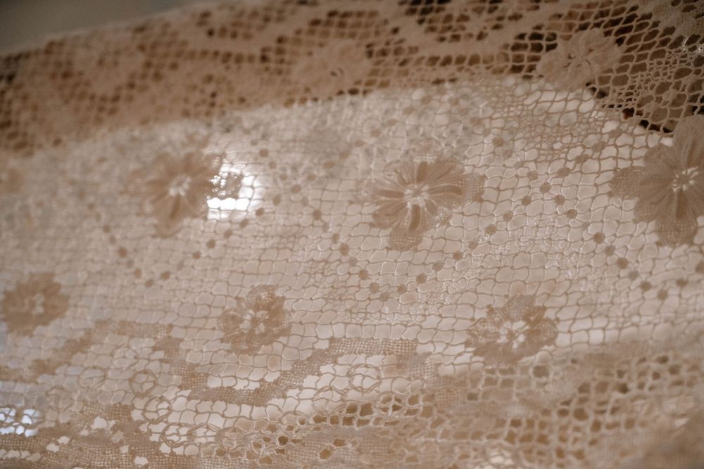 Close-up of delicate cream lace fabric featuring intricate floral patterns and fine mesh texture.