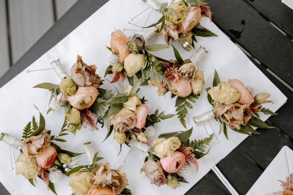 Elegant wedding boutonnieres with blush pink and cream flowers arranged on a white surface.