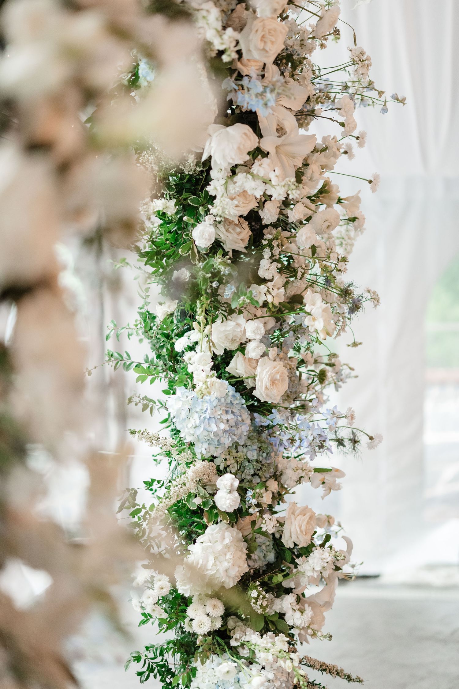 Lush floral arch adorned with white roses, hydrangeas, and greenery for an elegant wedding ceremony.