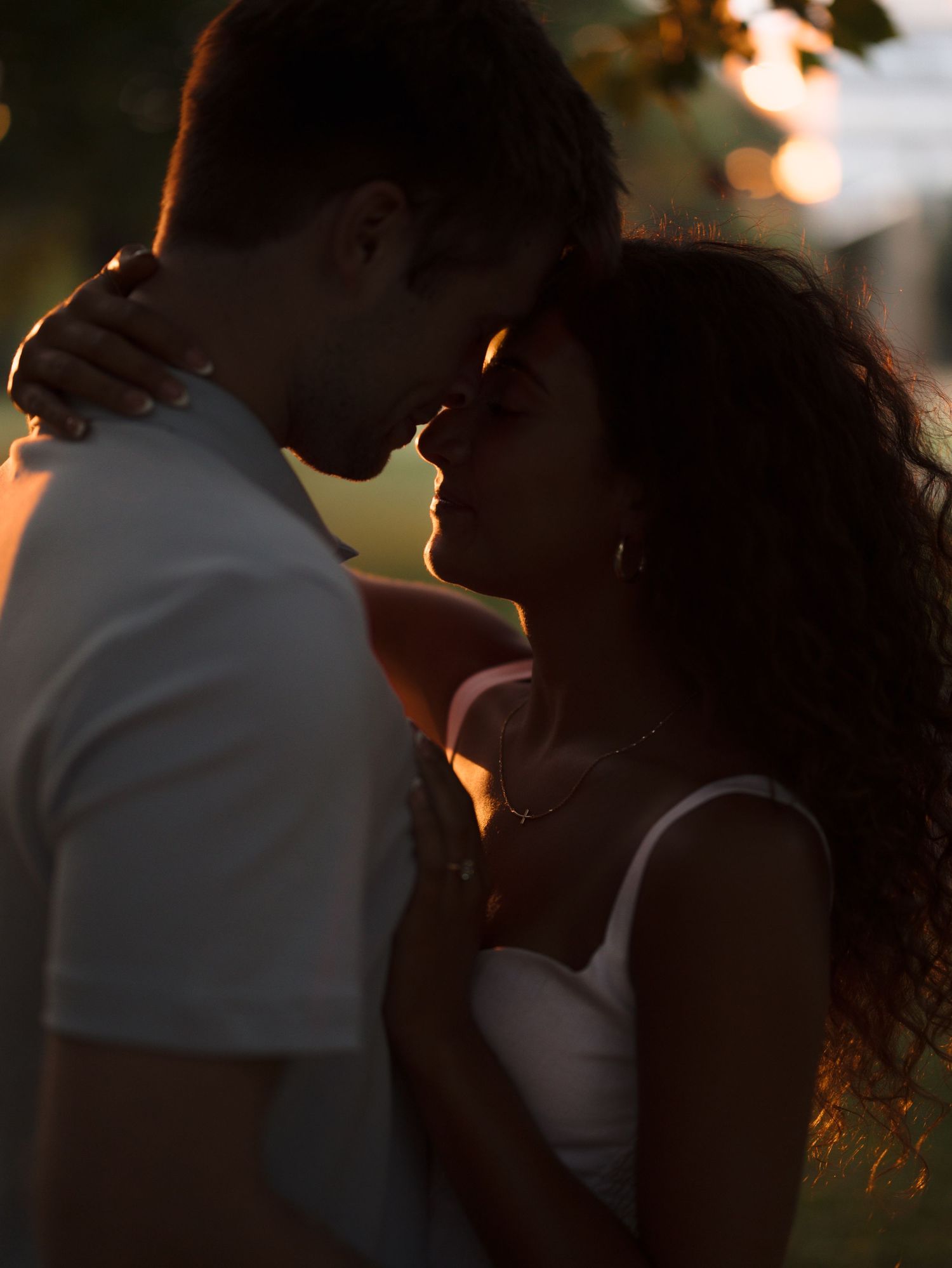 Romantic couple sharing intimate moment at golden hour, faces close together in warm sunlight.