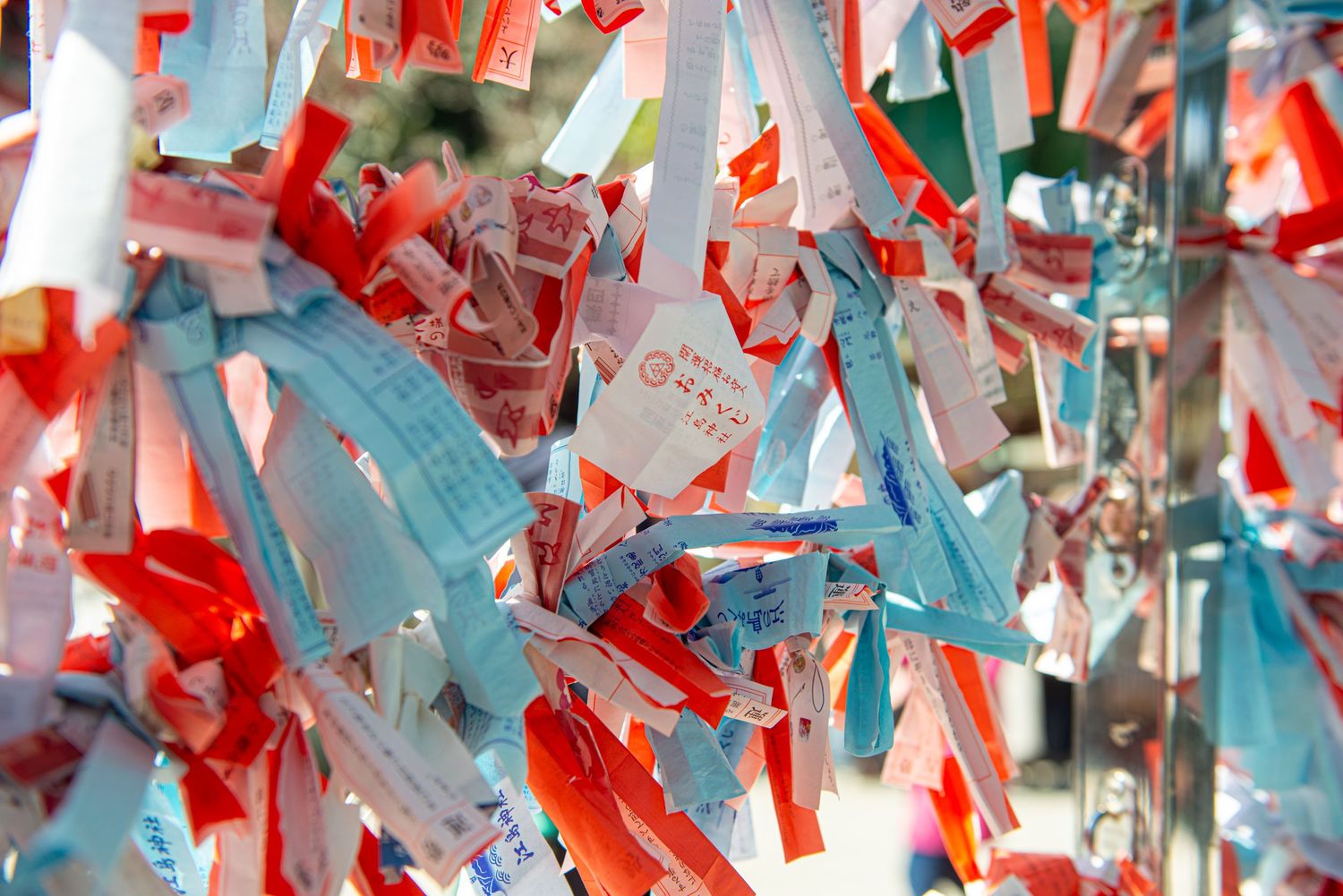 Colorful paper wishes and fortune slips tied to a traditional Japanese shrine wall, creating a vibrant display.