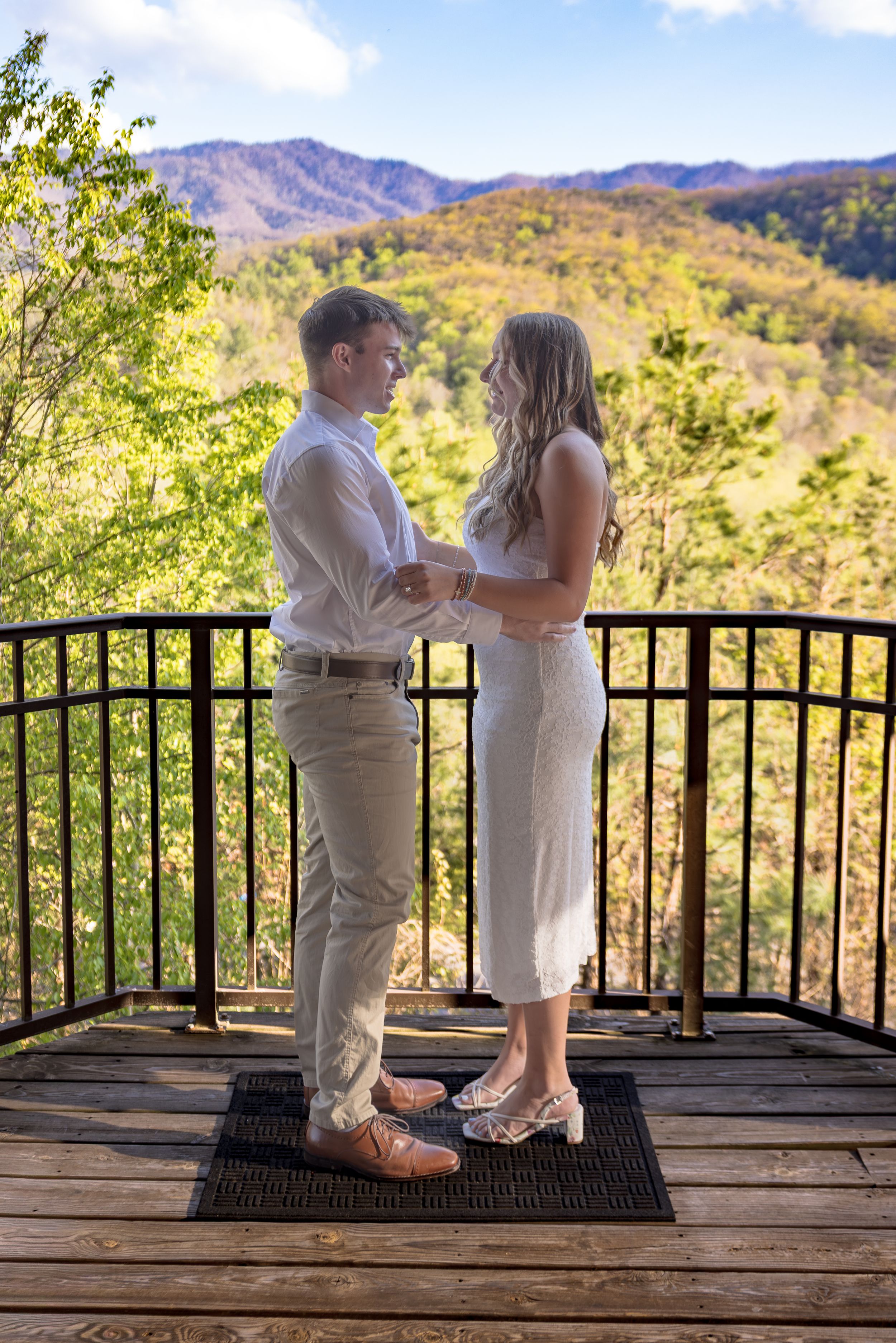 Couple holding hands on a wooden deck with stunning mountain views during an outdoor wedding ceremony.
