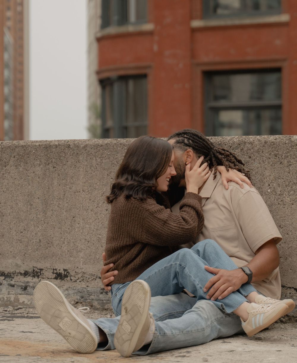 Couple sharing a romantic kiss while sitting together on urban steps, embracing each other tenderly.