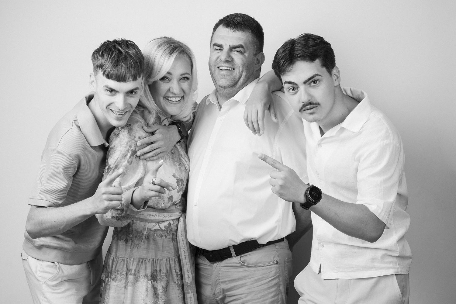 Family portrait of four people, two adults and two children, posing together against a light gray background.