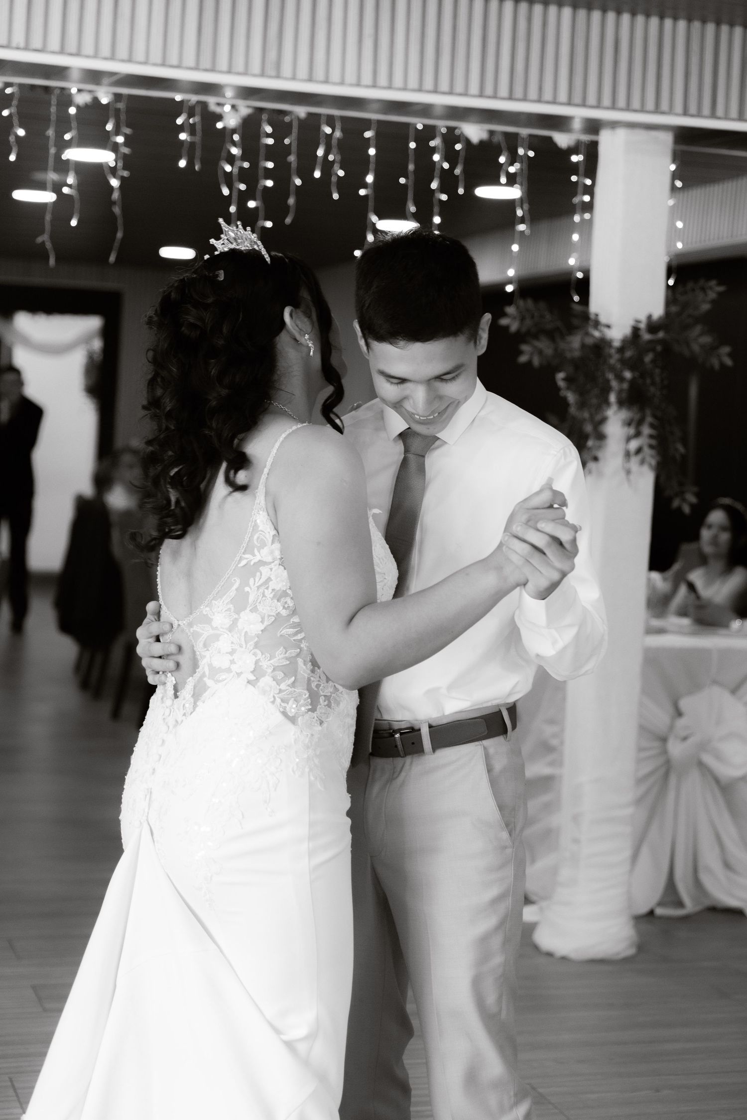 Bride and groom share intimate first dance in black and white wedding reception photo.