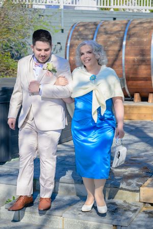 Le marié en costume beige marchant dans l'allée au bras de sa mère pour la cérémonie de mariage au Lac-Saint-Jean.