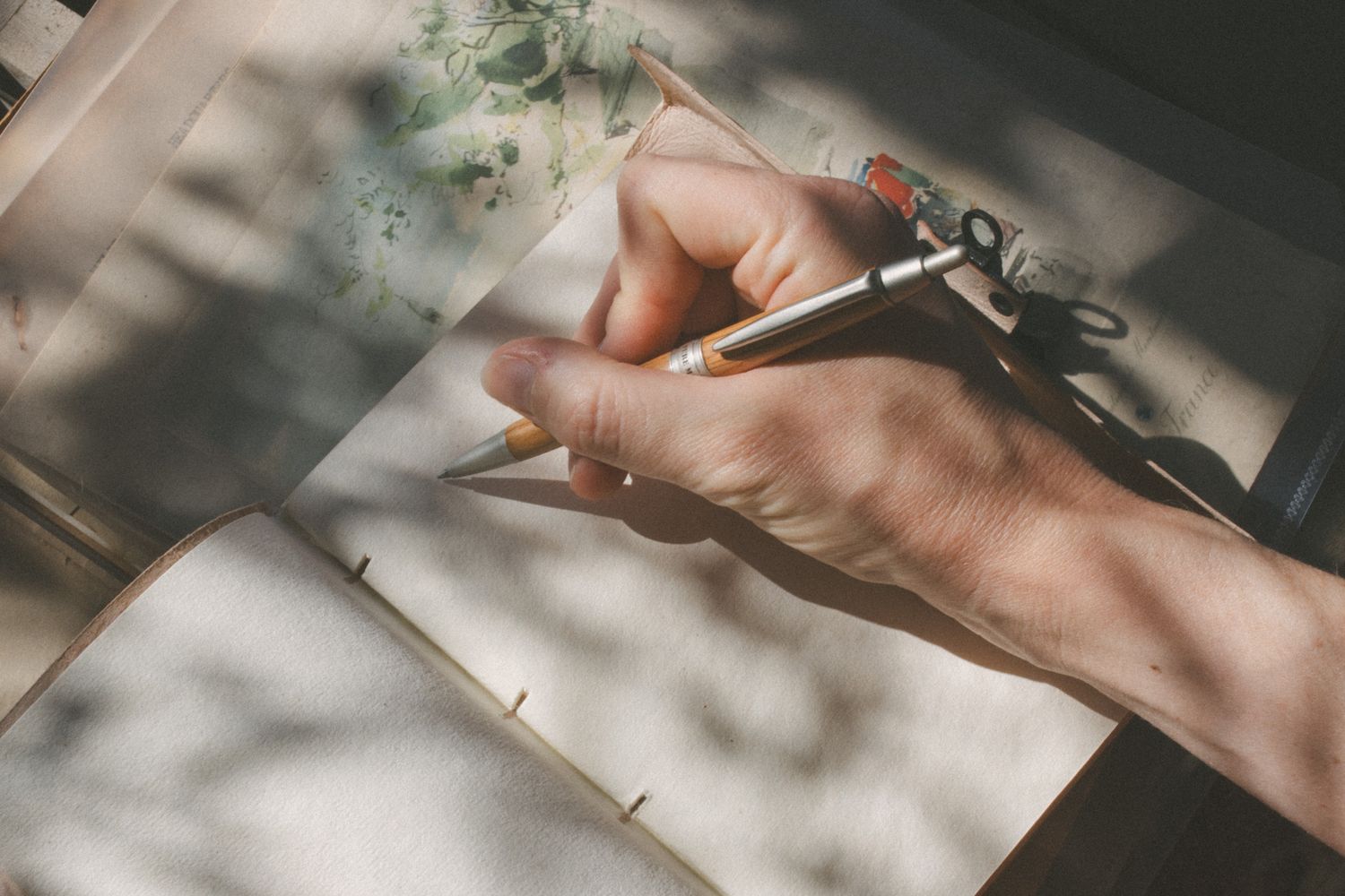 Person writing in a notebook in natural light.