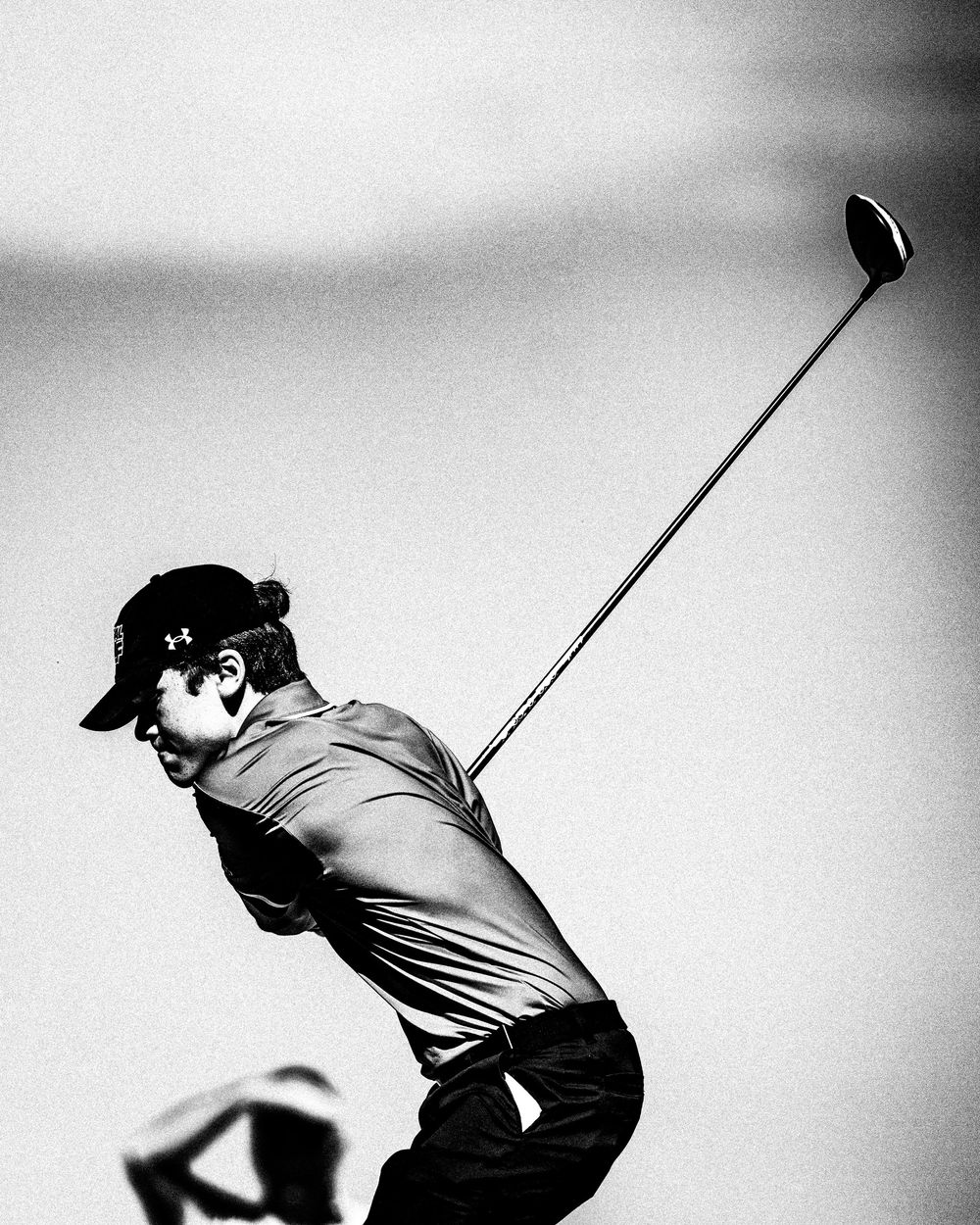 Black and white action shot of a golfer completing a powerful drive swing.