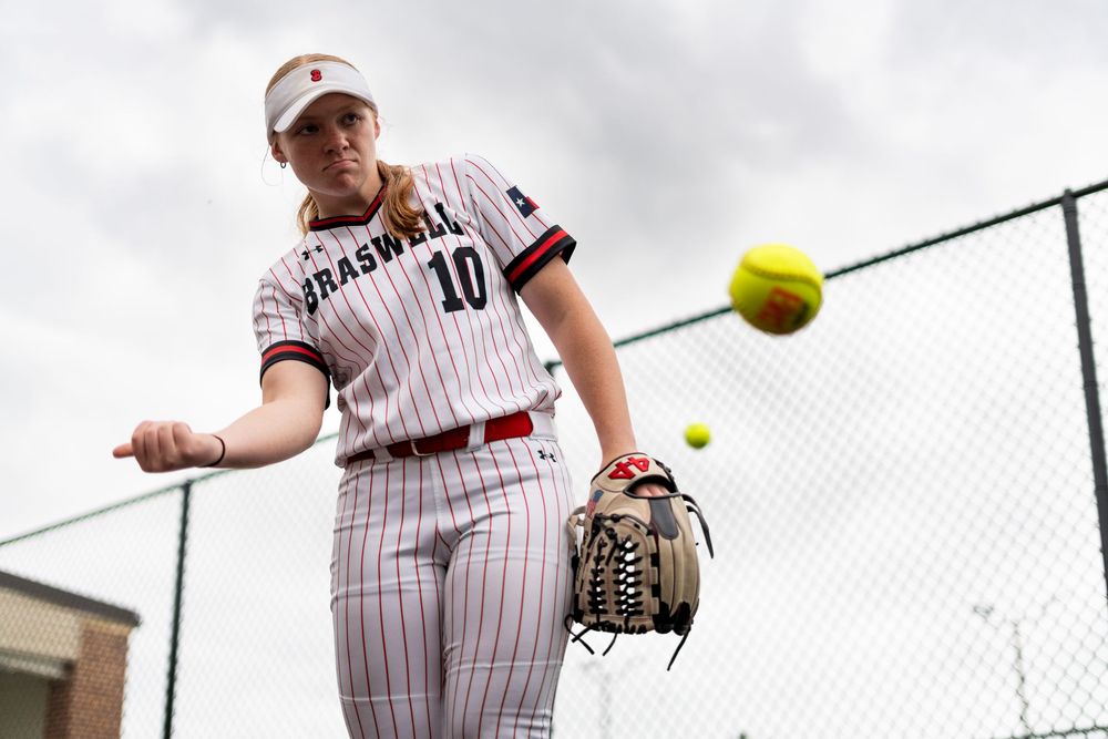 Softball player number 10 in Braswell uniform hits a yellow ball during practice.