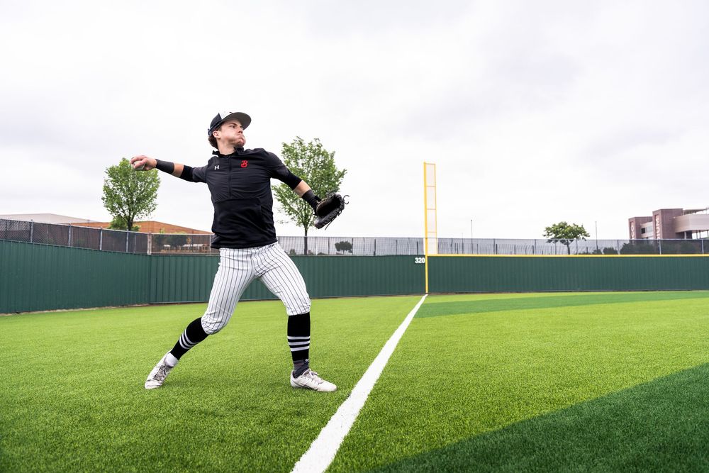 Baseball player throwing ball on a green turf field during practice.