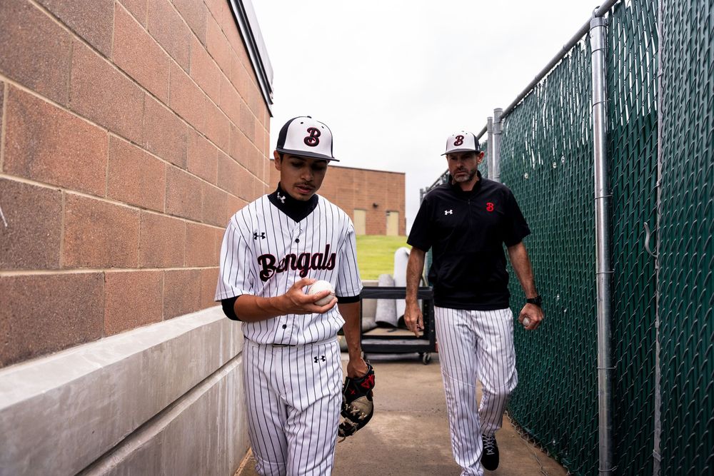 Bengals baseball player and coach walk through a tunnel toward the field before a game.