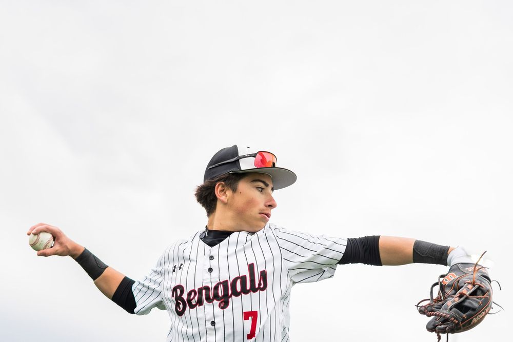 Bengals baseball player number 7 winds up to throw during an outdoor game.