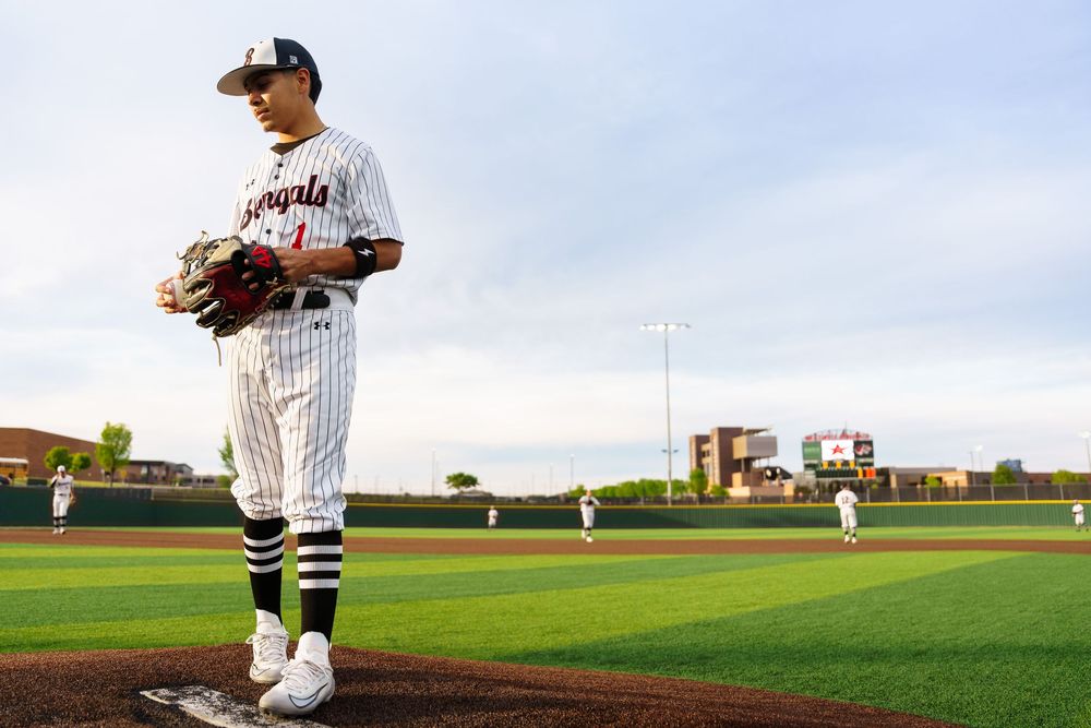 Baseball player in pinstripe uniform stands on the pitching mound at a well-maintained outdoor stadium.