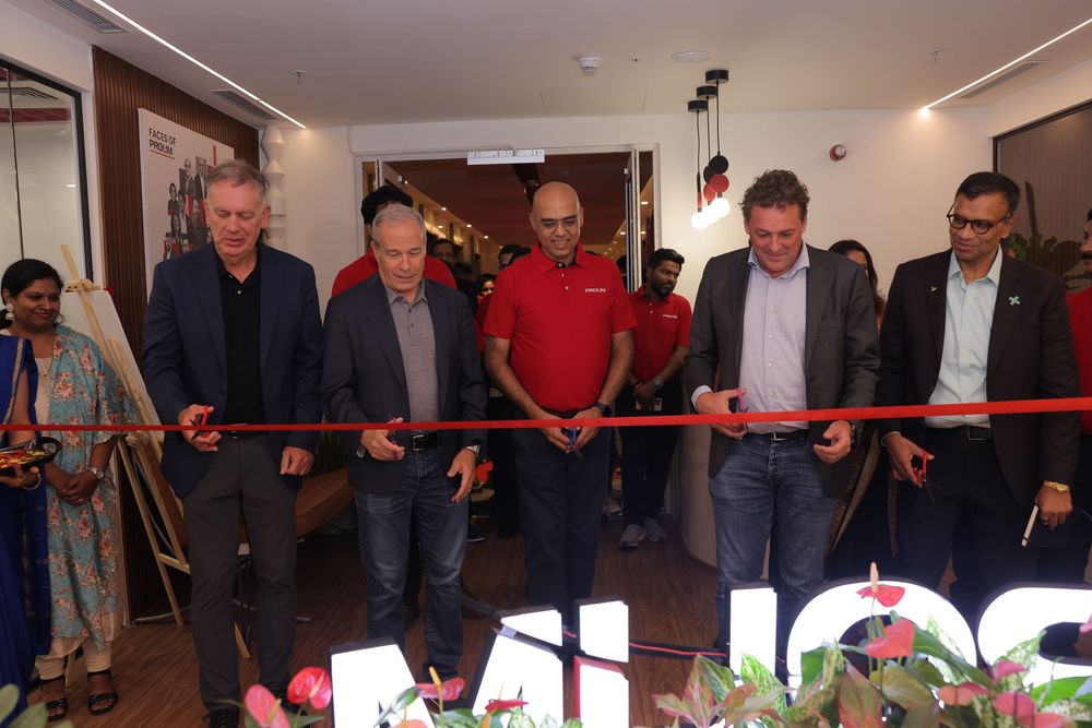 Five men cutting a red ribbon at a grand opening ceremony inside a modern retail store.