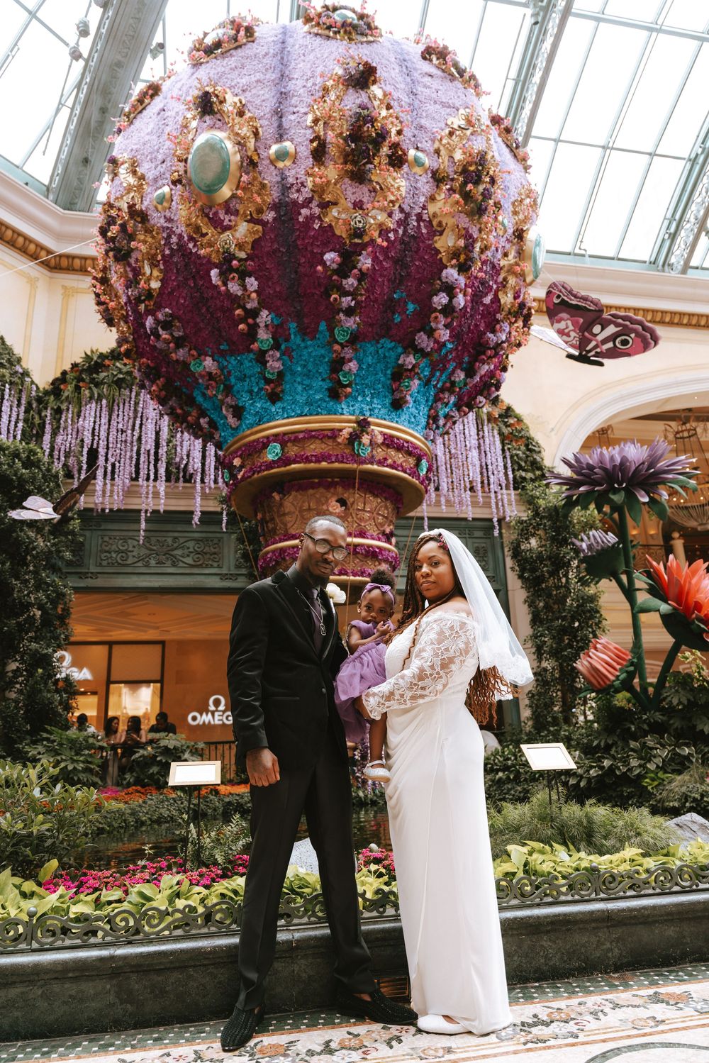Newlywed couple posing in front of a floral hot air balloon display at the Bellagio Conservatory in Las Vegas.