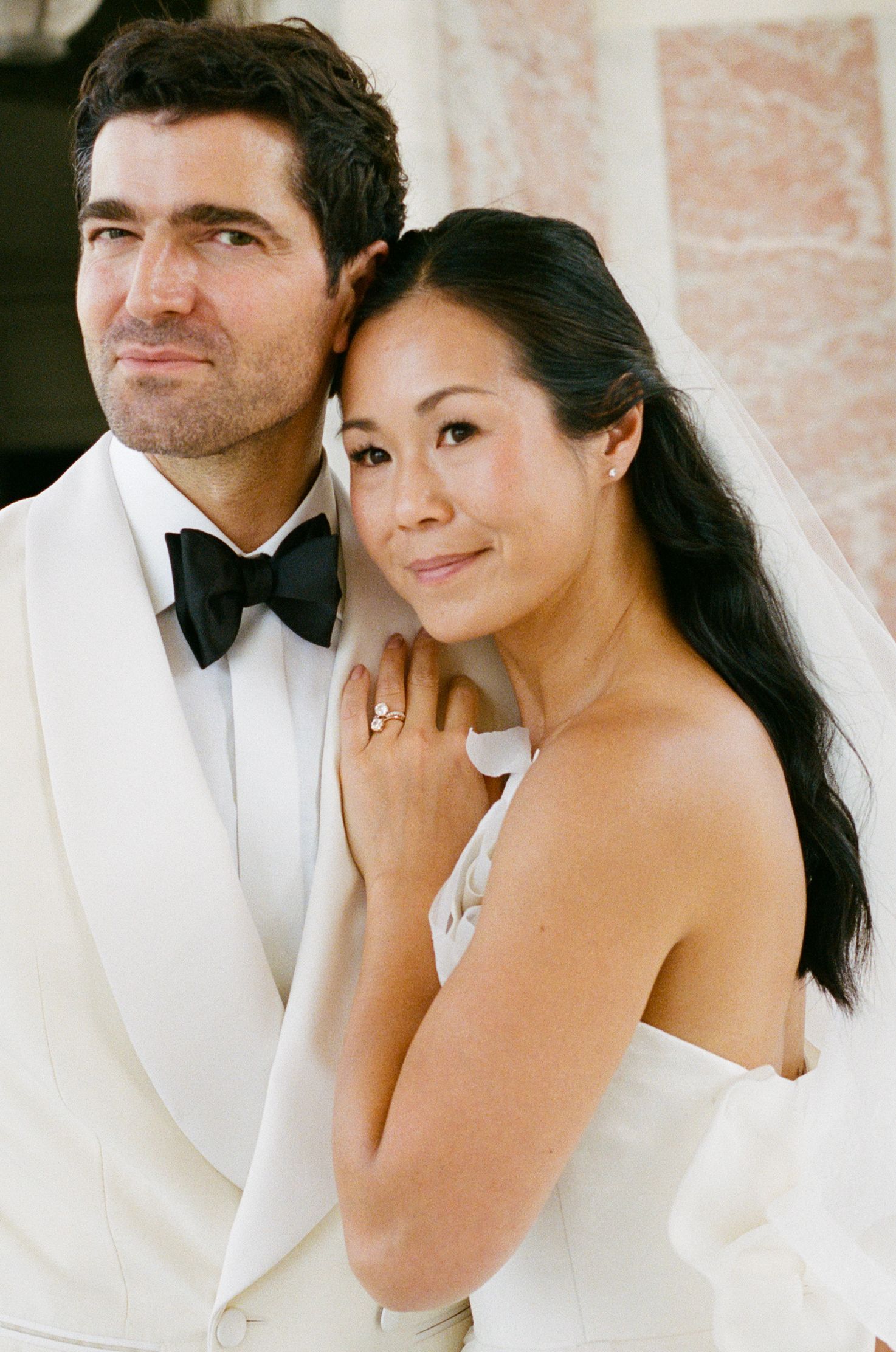 Elegant bride and groom posing together on their wedding day, groom in white tuxedo with bow tie. Le Grand Trianon, Versailles wedding