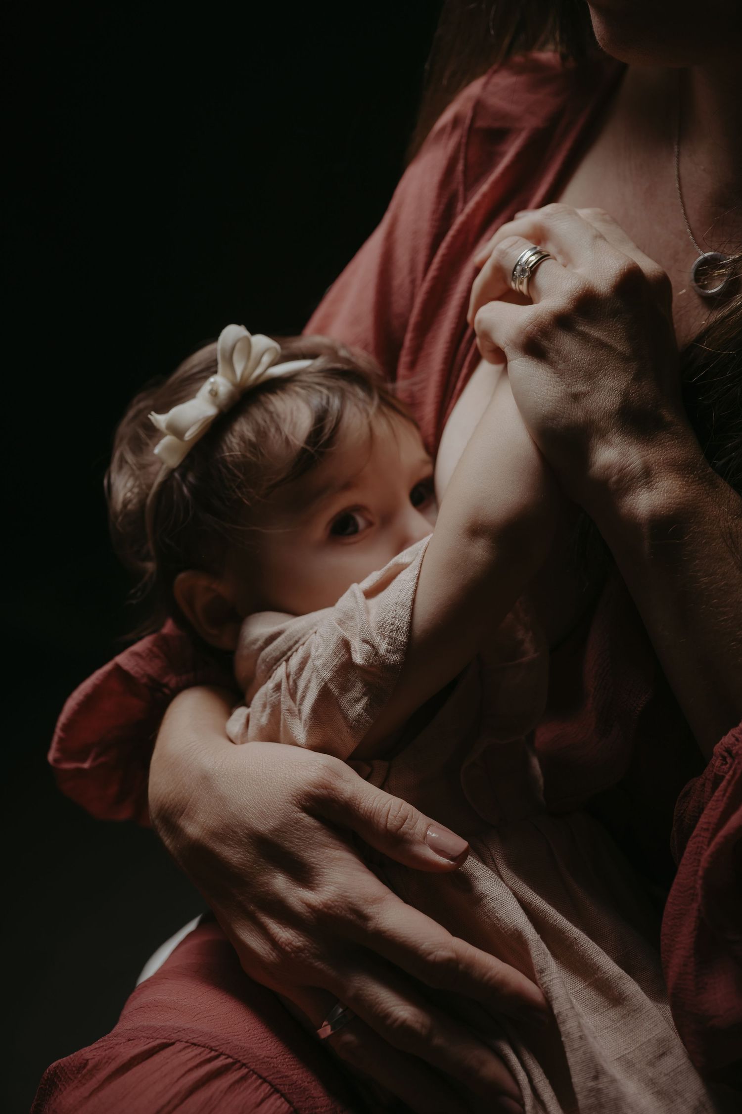 A mother tenderly breastfeeding her infant in soft, moody lighting, capturing an intimate bonding moment.