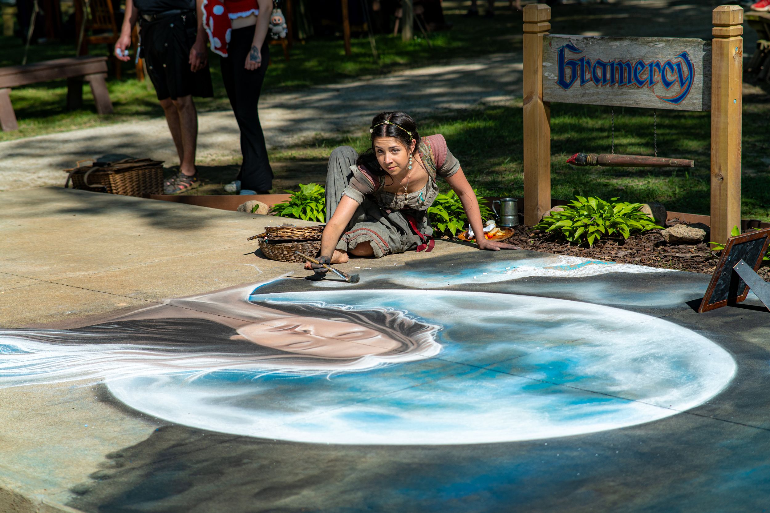Performer in a mermaid costume beside a pool at an outdoor festival