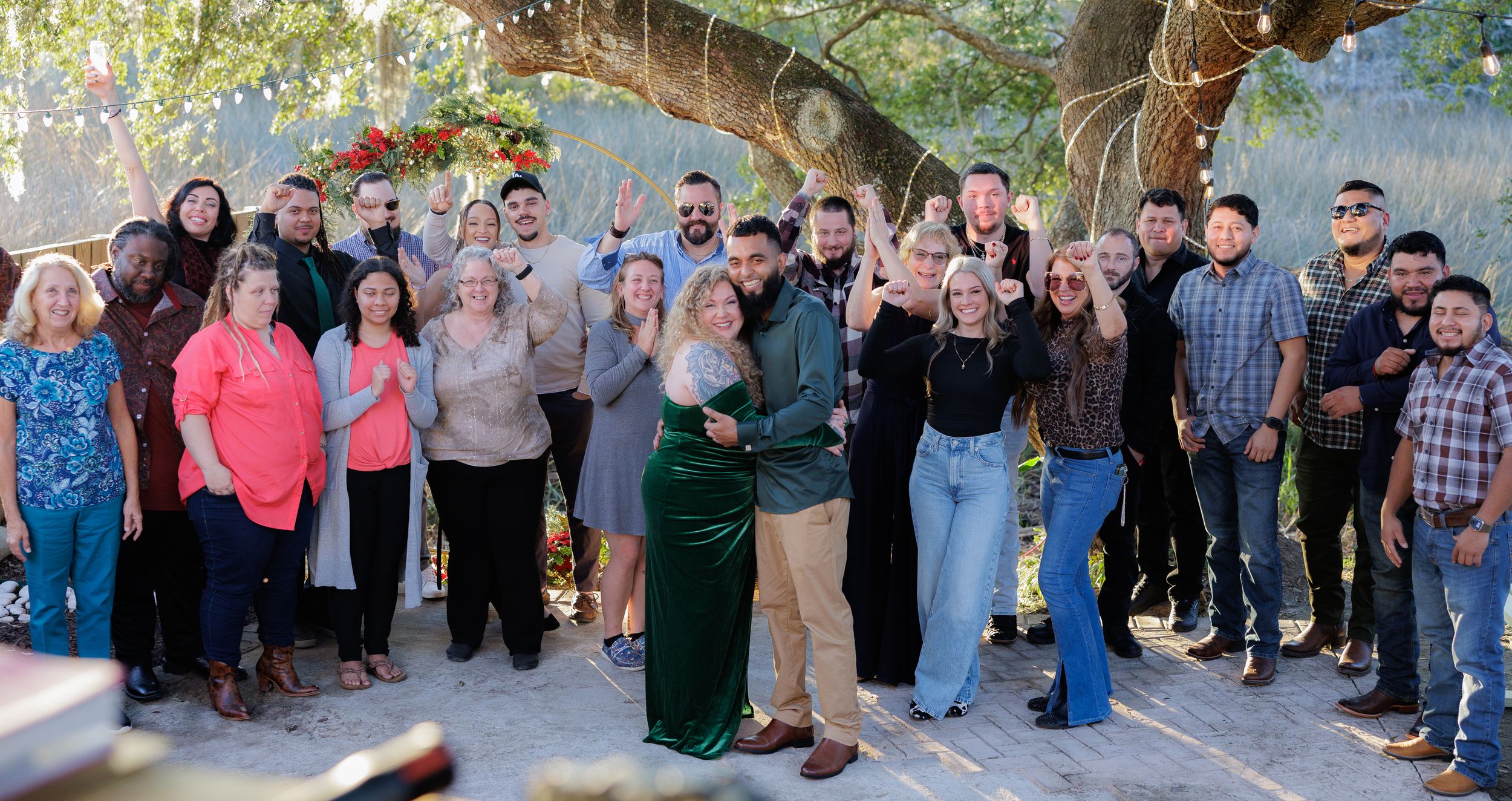 Large group photo of wedding guests gathered outside for a celebration.