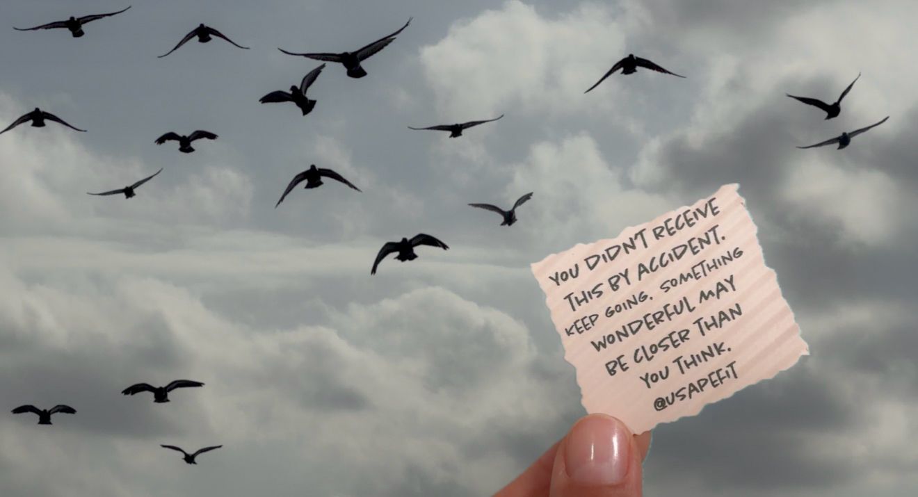 Hand holding a note against cloudy sky with flying birds, inspirational message from Budapest.
