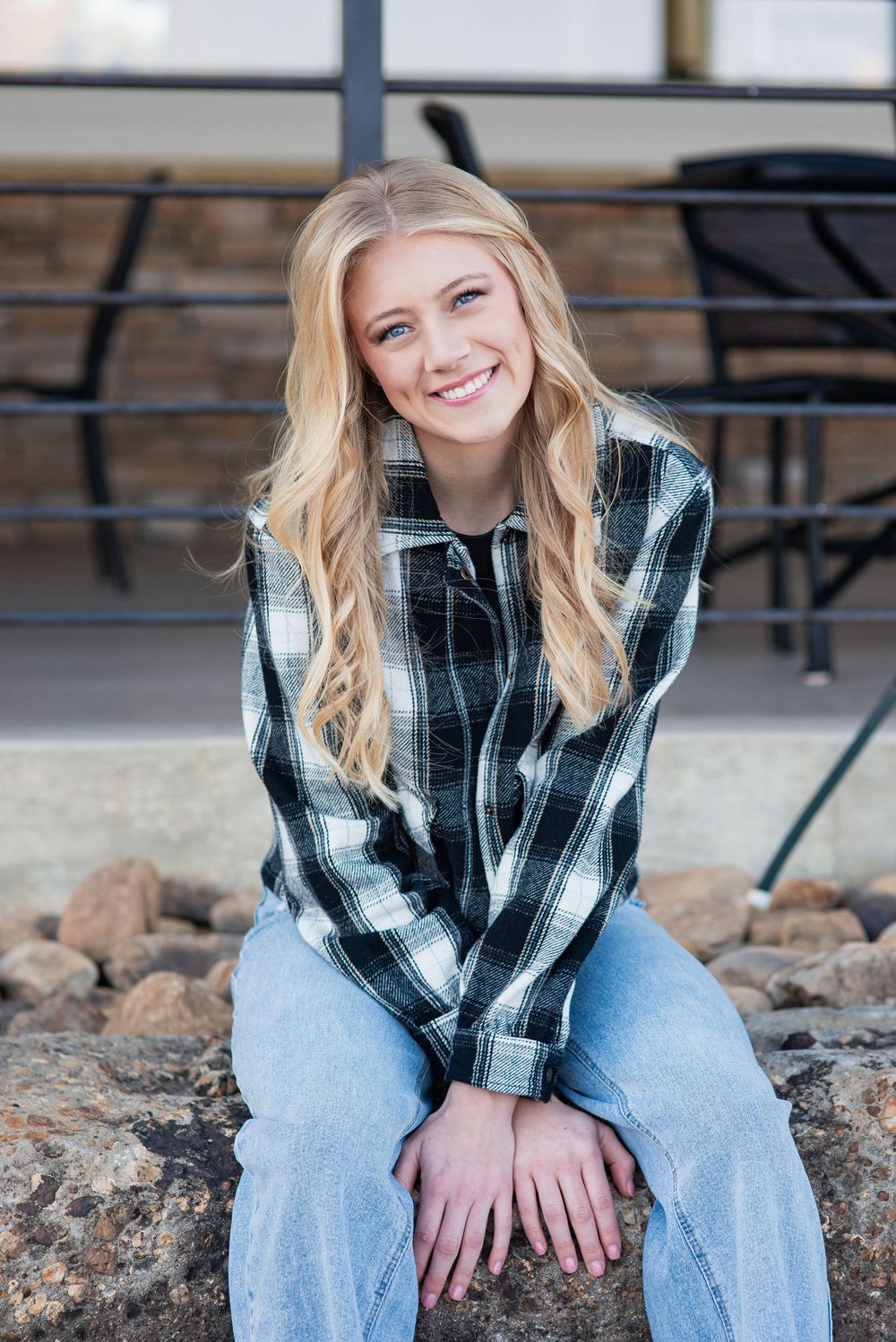 High school senior portrait sitting on a rock wall