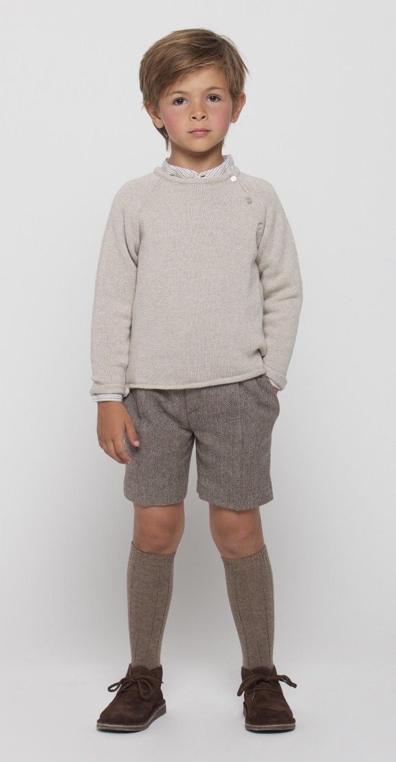 Young boy wearing beige knit sweater, gray shorts, knee-high socks, and brown lace-up shoes on white background.