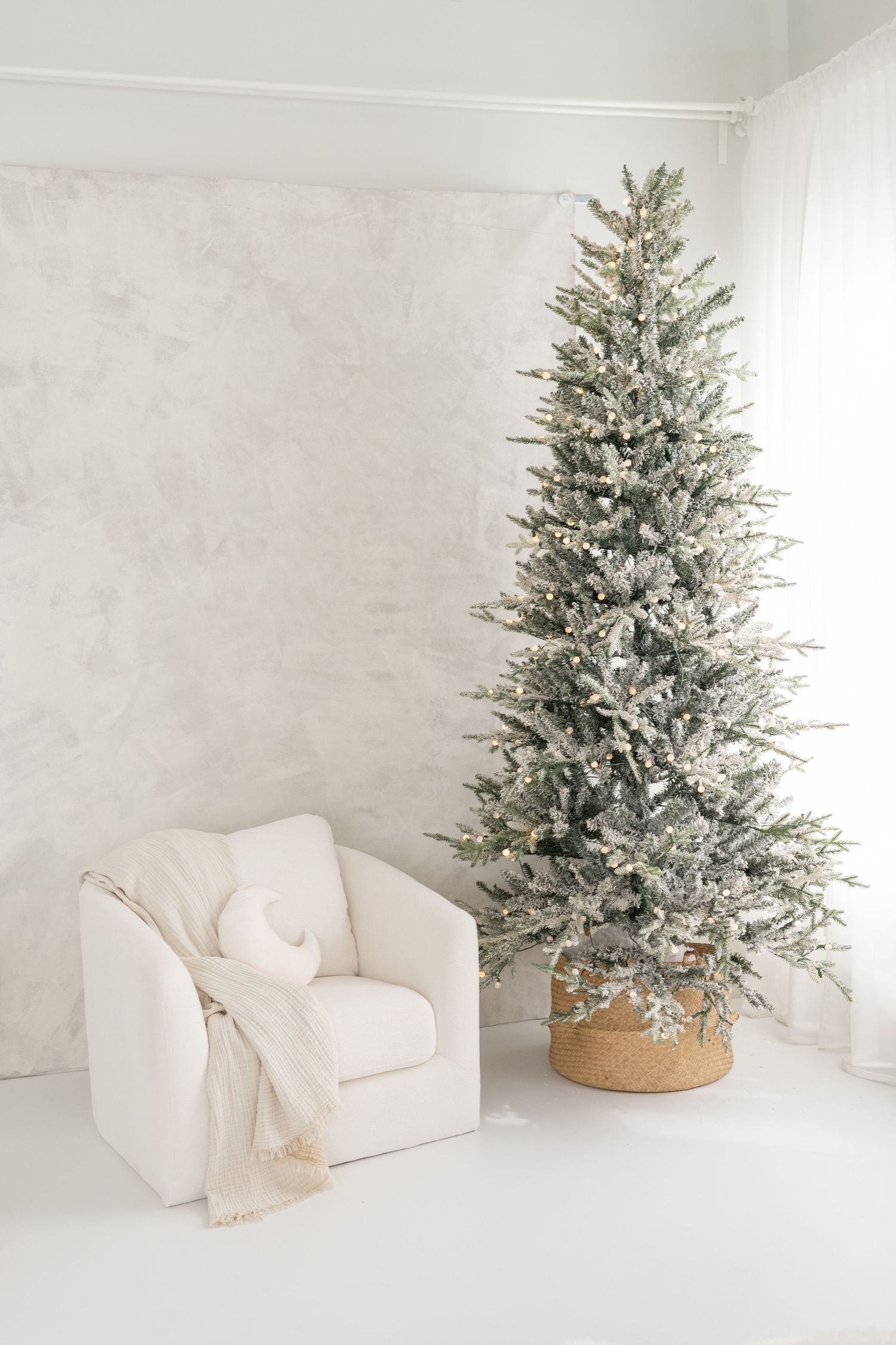 Décor fine art lumineux et épuré avec un sapin enneigé et une toile peinte à la main au studio de St-Augustin pour les séances de Noël 2026