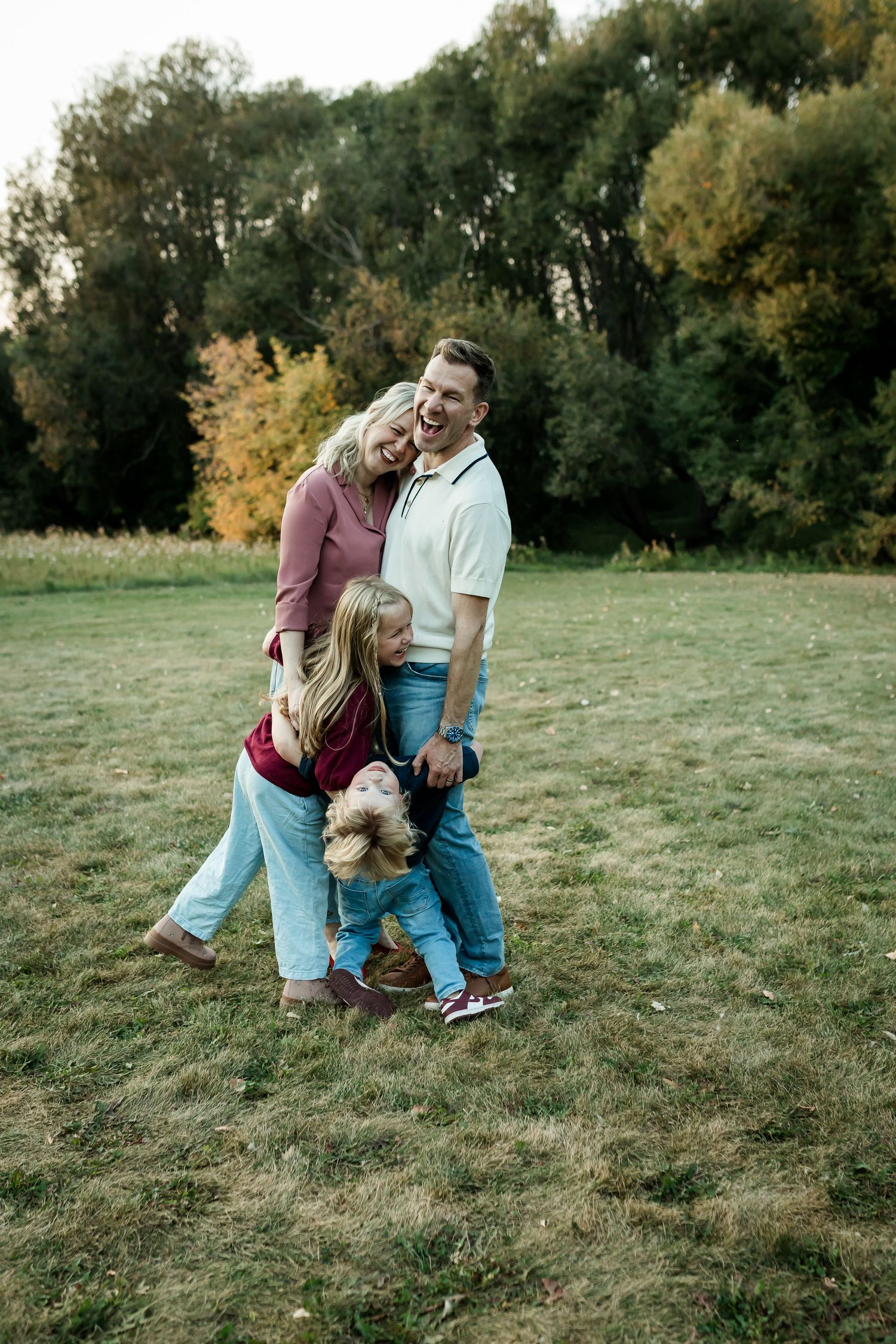 Family laughing and playing together during a candid fall family photography session in Calgary.