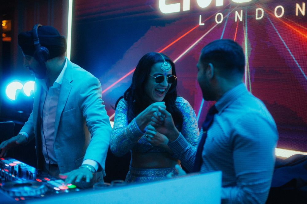 Candid photo of guests at DJ booth at a wedding