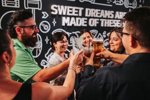 Group of friends toasting drinks together at a bar with Sweet Dreams Are Made of These wall mural.