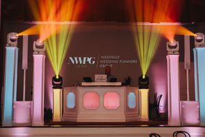Nashville Wedding Planners Group branded DJ booth with colorful stage lighting at an elegant wedding venue.