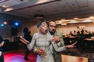 Couple dancing energetically at a wedding reception, expressing fun and joy on the dance floor.
