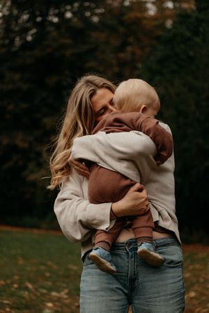 A mom kissing her toddler in the park