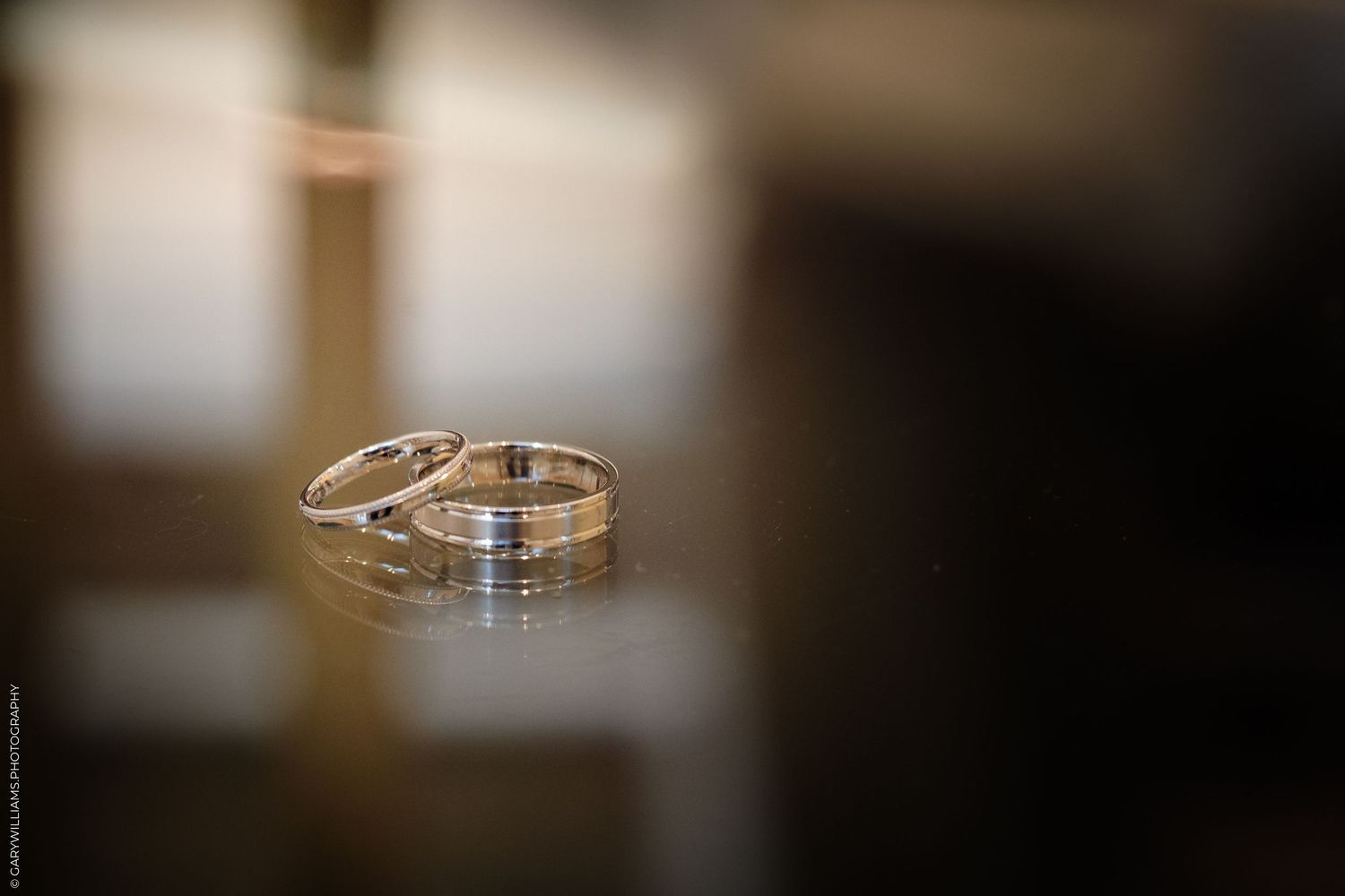 Two silver wedding bands resting on a reflective dark surface, symbolizing love and commitment.