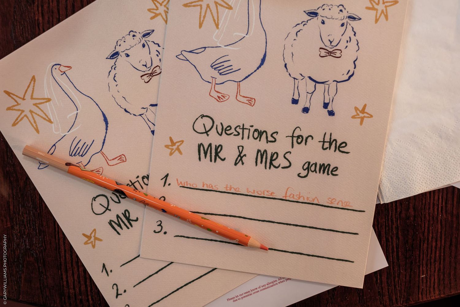 Mr & Mrs game question cards with farm animal illustrations and a pencil on a wooden table.