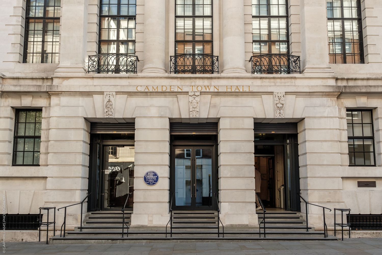 Grand neoclassical Hackney Town Hall entrance with stone columns, balconies, and blue heritage plaque in London.