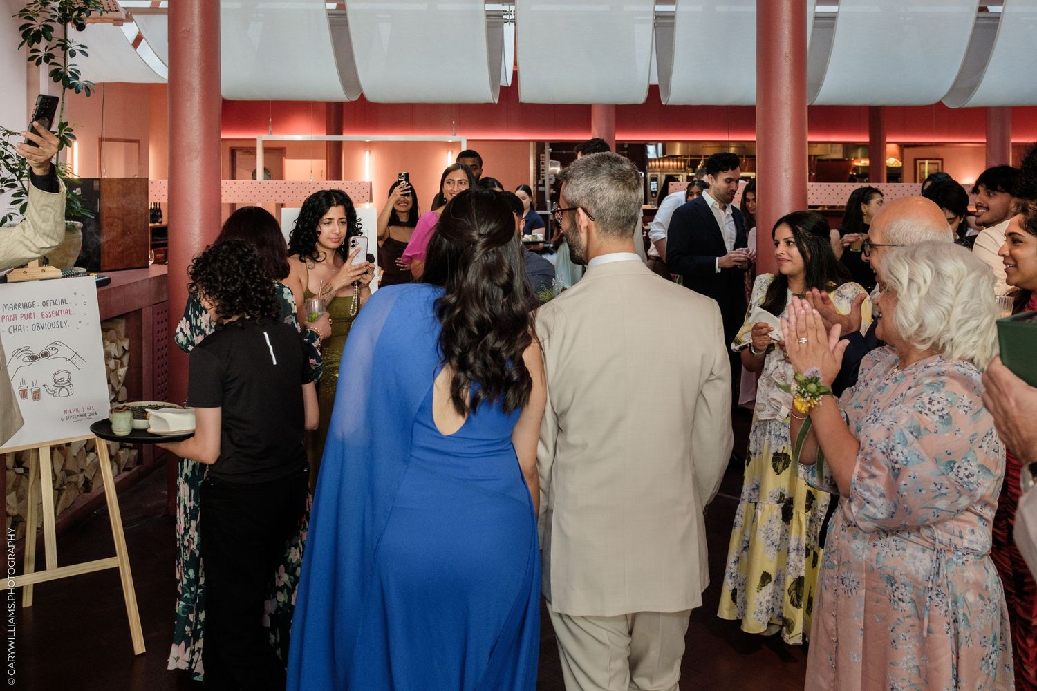 Elegantly dressed guests mingling at an indoor social event, featuring colorful formal attire in a modern venue.