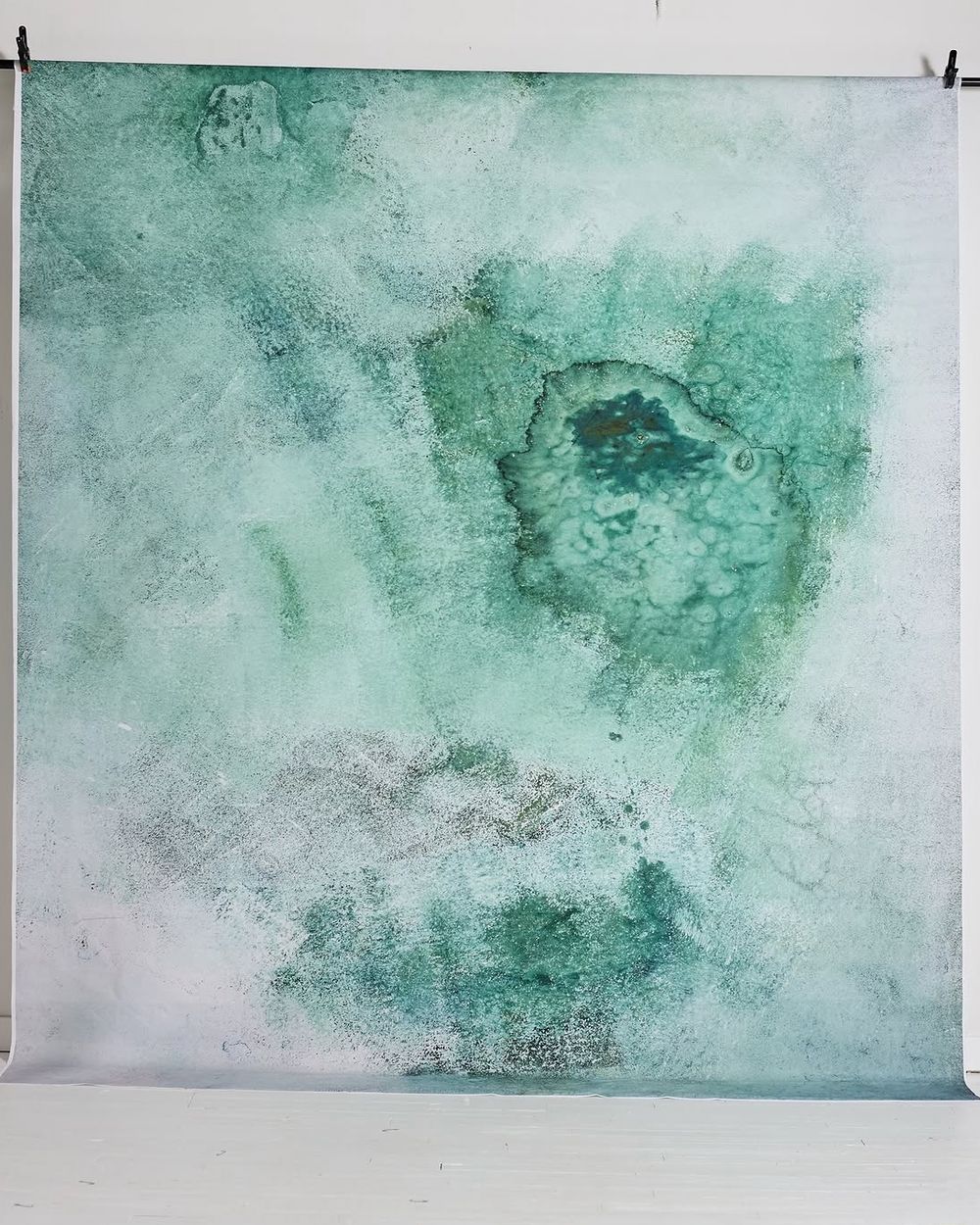 Soft green and white abstract textured photography backdrop with organic paint patterns in a studio setting.