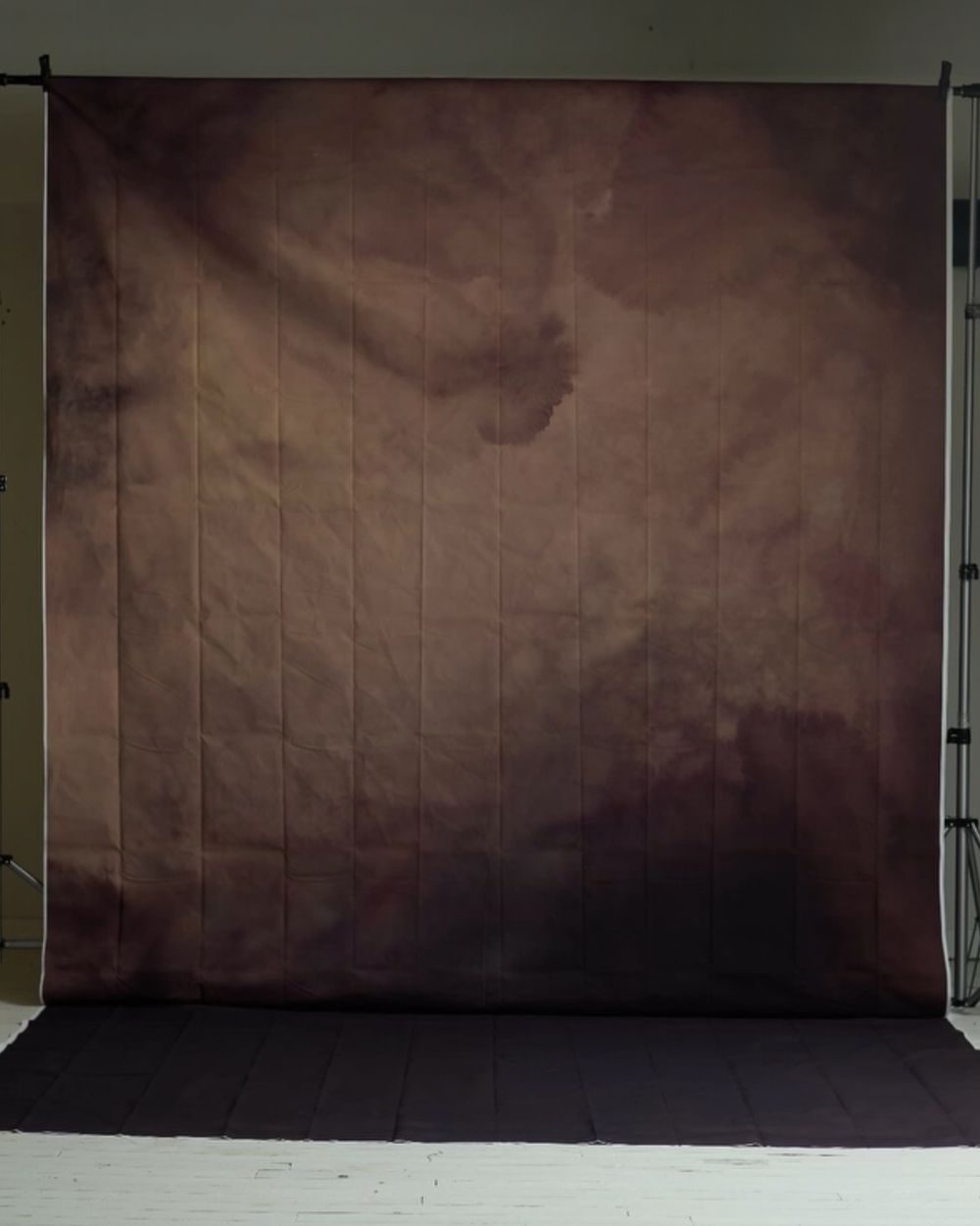 Moody brown and mauve abstract cloudy photography backdrop with vertical texture hanging in a studio.