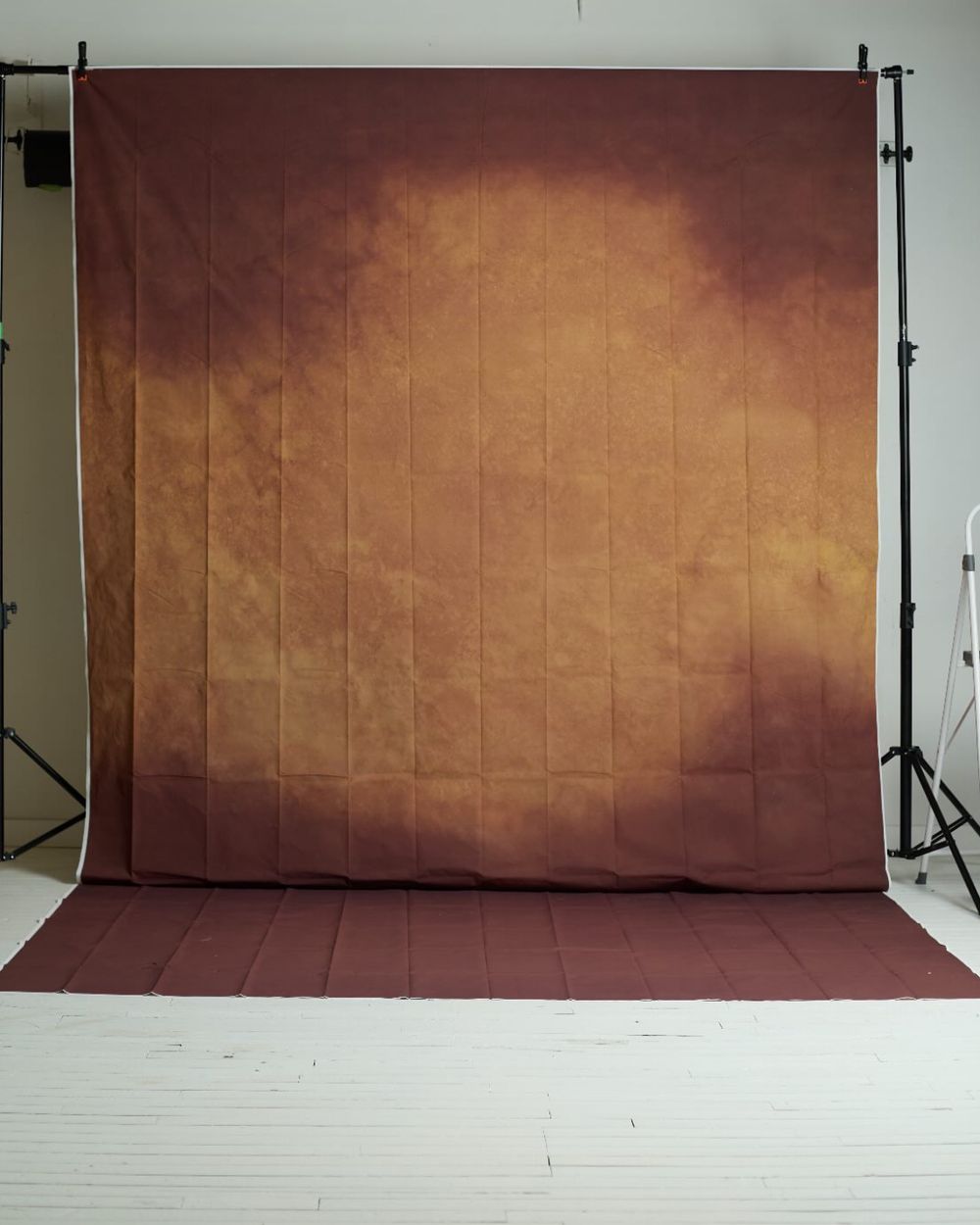 Warm brown and golden abstract photography backdrop displayed on a stand in a studio.
