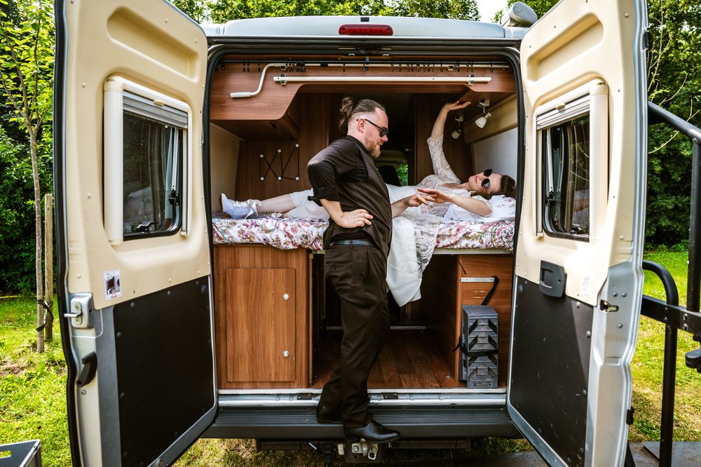 Speelse huwelijksfoto van een koppel in een camper, spontaan vastgelegd door huwelijksfotograaf Bart Boodts in België.