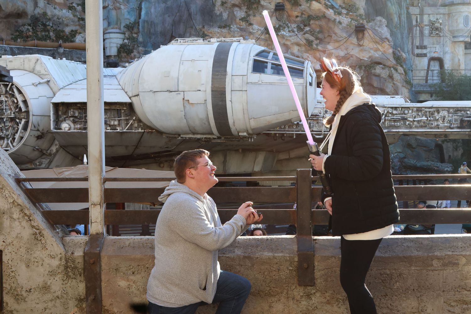 My brother kneels to propose with a ring while the other holds a glowing pink toy lightsaber.