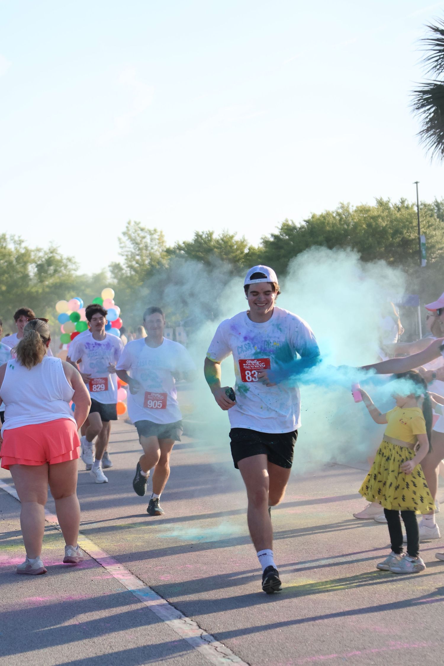 Runner moves through a cloud of blue powder during an outdoor color run.